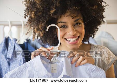 Stock Photo - Mixed race woman shopping in clothing store. Fotosearch
