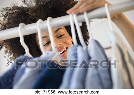 Stock Photograph - Mixed race woman shopping in clothing store. Fotosearch