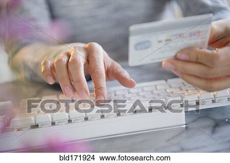 Picture - Mixed race woman shopping online with credit card. Fotosearch