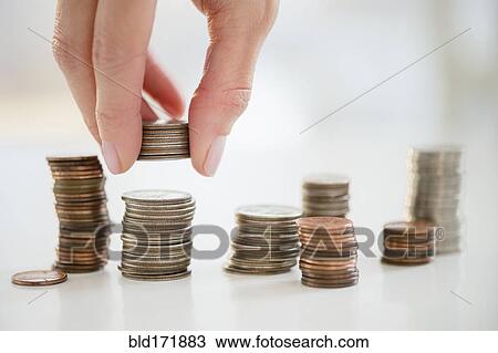 Stock Image - Mixed race woman stacking coins. Fotosearch