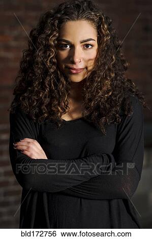 Stock Photograph - Mixed race woman standing with arms crossed. Fotosearch