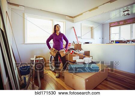 Stock Image - Mixed race woman surveying remodeling project. Fotosearch