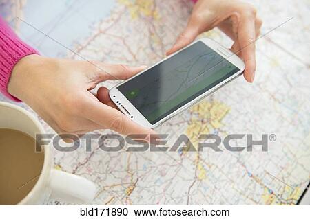 Stock Image - Mixed race woman taking cell phone photograph of roadmap. Fotosearch