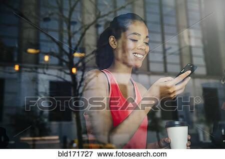 Stock Photo - Mixed race woman using cell phone in cafe. Fotosearch
