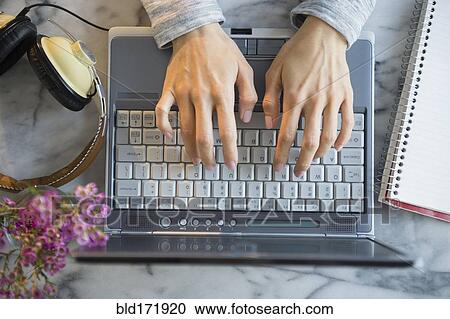 Stock Image - Mixed race woman using laptop at table. Fotosearch