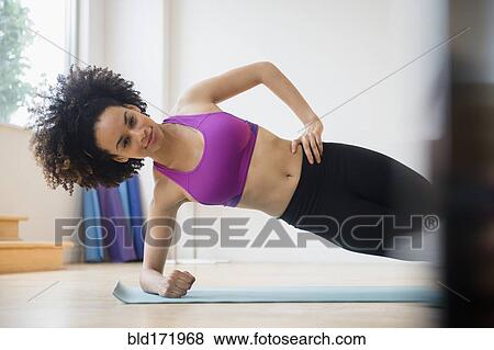Stock Photo - Mixed race woman working out in gymnasium. Fotosearch