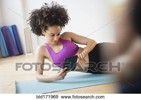 Stock Photo - Mixed race woman working out with digital tablet in gymnasium. Fotosearch