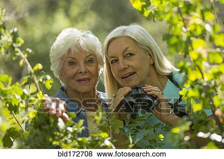 Stock Photo - Older Caucasian women bird-watching outdoors. Fotosearch