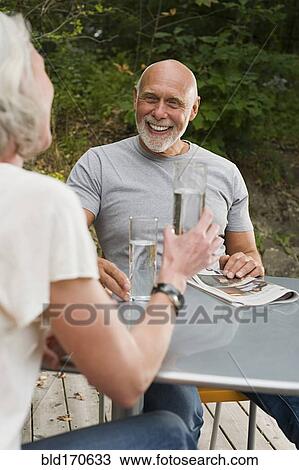 Older couple drinking water at table outdoors View Large Photo Image Stock Image - Older couple drinking water at table outdoors. Fotosearch