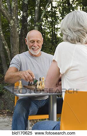 Stock Photography - Older couple playing chess in backyard. Fotosearch