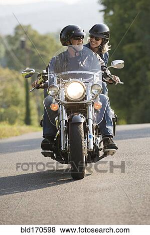Older couple riding motorcycle on empty road View Large Photo Image Stock Photo - Older couple riding motorcycle on empty road. Fotosearch