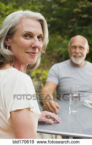 Stock Photo - Older couple sitting at table outdoors. Fotosearch