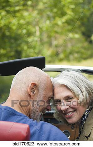 Stock Image - Older couple sitting in convertible. Fotosearch