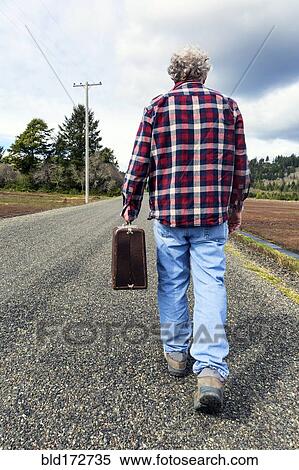 Older man carrying suitcase on rural road View Large Photo Image Stock Photography - Older man carrying suitcase on rural road. Fotosearch