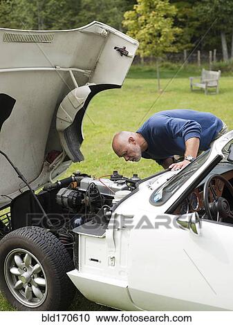 Older man examining broken-down convertible in park View Large Photo Image Stock Image - Older man examining broken-down convertible in park. Fotosearch