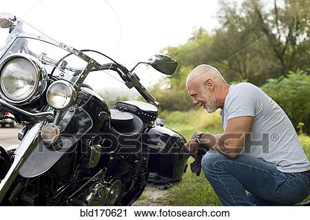 Older man repairing motorcycle in park View Large Photo Image Stock Image - Older man repairing motorcycle in park. Fotosearch