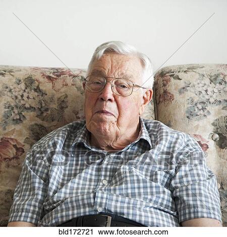 Stock Image - Older man sitting on sofa. Fotosearch