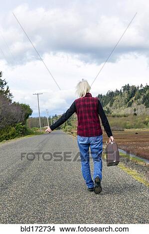 Older woman hitch hiking on rural road View Large Photo Image Picture - Older woman hitch hiking on rural road. Fotosearch