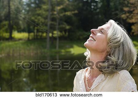 Stock Image - Older woman standing in park. Fotosearch