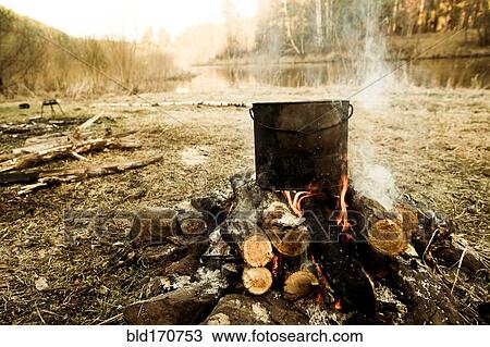 Pot cooking on campfire in rural field View Large Photo Image Stock Image - Pot cooking on campfire in rural field. Fotosearch