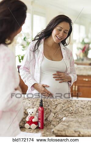 Picture - Pregnant Hispanic woman holding her belly. Fotosearch