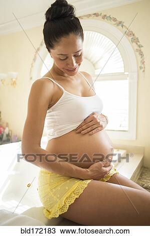 Pregnant Hispanic woman holding her belly View Large Photo Image Stock Image - Pregnant Hispanic woman holding her belly. Fotosearch