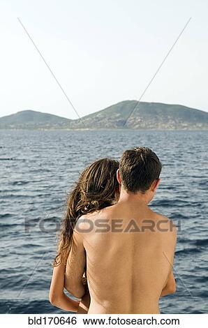 Stock Photograph - Rear view of couple admiring ocean view. Fotosearch