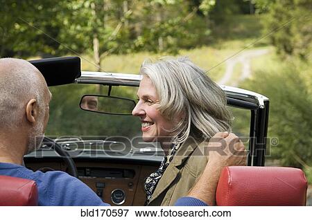 Stock Photo - Rear view of older couple driving convertible. Fotosearch
