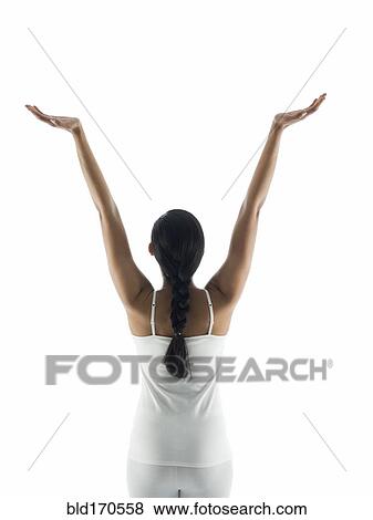 Stock Photo - Rear view of woman meditating with arms raised. Fotosearch