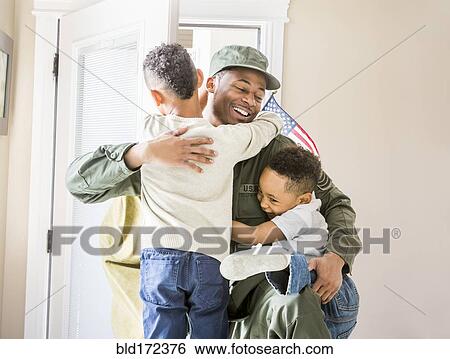 Stock Photograph - Returning soldier hugging children at door. Fotosearch