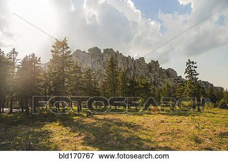 Stock Photo - Rocky hilltop over forest in remote field. Fotosearch