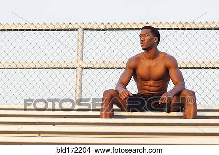 Picture - Serious Black athlete siting on bleachers. Fotosearch