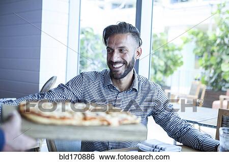 Stock Photograph - Server bringing diner pizza in restaurant. Fotosearch