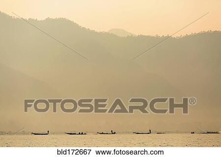 Stock Photo - Silhouette of canoes floating on rural lake. Fotosearch