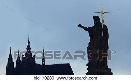 Stock Image - Silhouette of statue and crucifix by church spires, Prague, Bohemia, Czech Republic, . Fotosearch