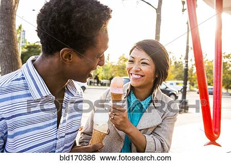 Stock Photograph - Smiling couple eating ice cream in park. Fotosearch