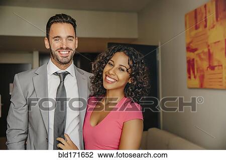 Stock Image - Smiling couple hugging in hotel room. Fotosearch