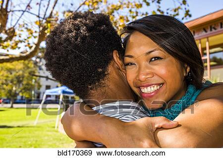 Stock Photo - Smiling couple hugging in park. Fotosearch