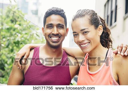 Stock Photograph - Smiling couple hugging on urban rooftop. Fotosearch