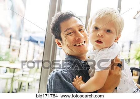 Smiling father holding son by window View Large Photo Image Picture - Smiling father holding son by window. Fotosearch