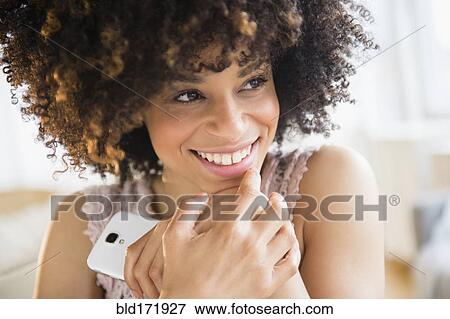 Smiling mixed race woman holding cell phone View Large Photo Image Stock Photo - Smiling mixed race woman holding cell phone. Fotosearch