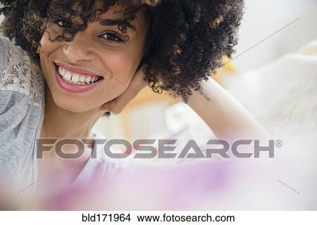 Smiling mixed race woman laying on bed View Large Photo Image Picture - Smiling mixed race woman laying on bed. Fotosearch