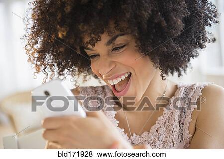 Stock Photo - Smiling mixed race woman using cell phone. Fotosearch