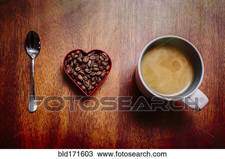 Stock Image - Spoon, beans and cup of coffee on counter. Fotosearch