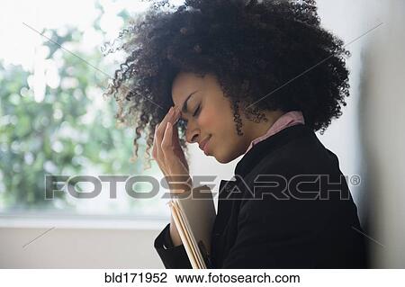 Stock Image - Stressed mixed race businesswoman rubbing her forehead. Fotosearch