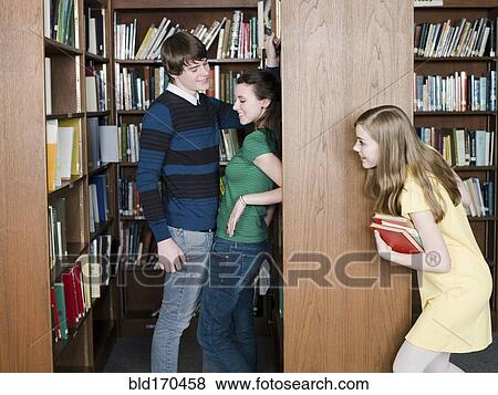 Stock Photo - Student eavesdropping on classmates in library. Fotosearch