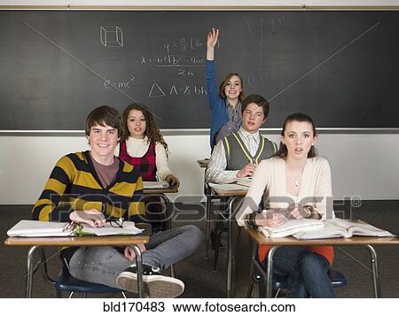 Stock Image - Student raising her hand in classroom. Fotosearch