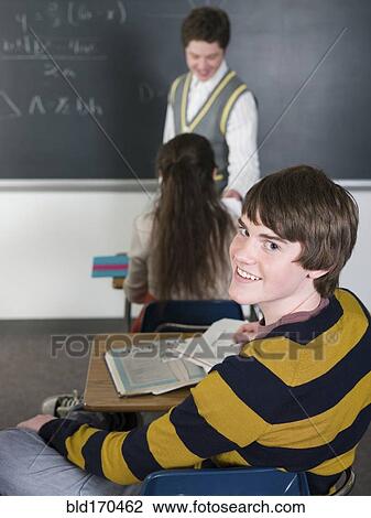 Student smiling at desk in classroom View Large Photo Image Stock Image - Student smiling at desk in classroom. Fotosearch