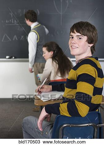 Student smiling at desk in classroom View Large Photo Image Stock Image - Student smiling at desk in classroom. Fotosearch