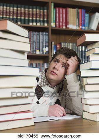 Stock Photography - Student staring at stacks of books in library. Fotosearch